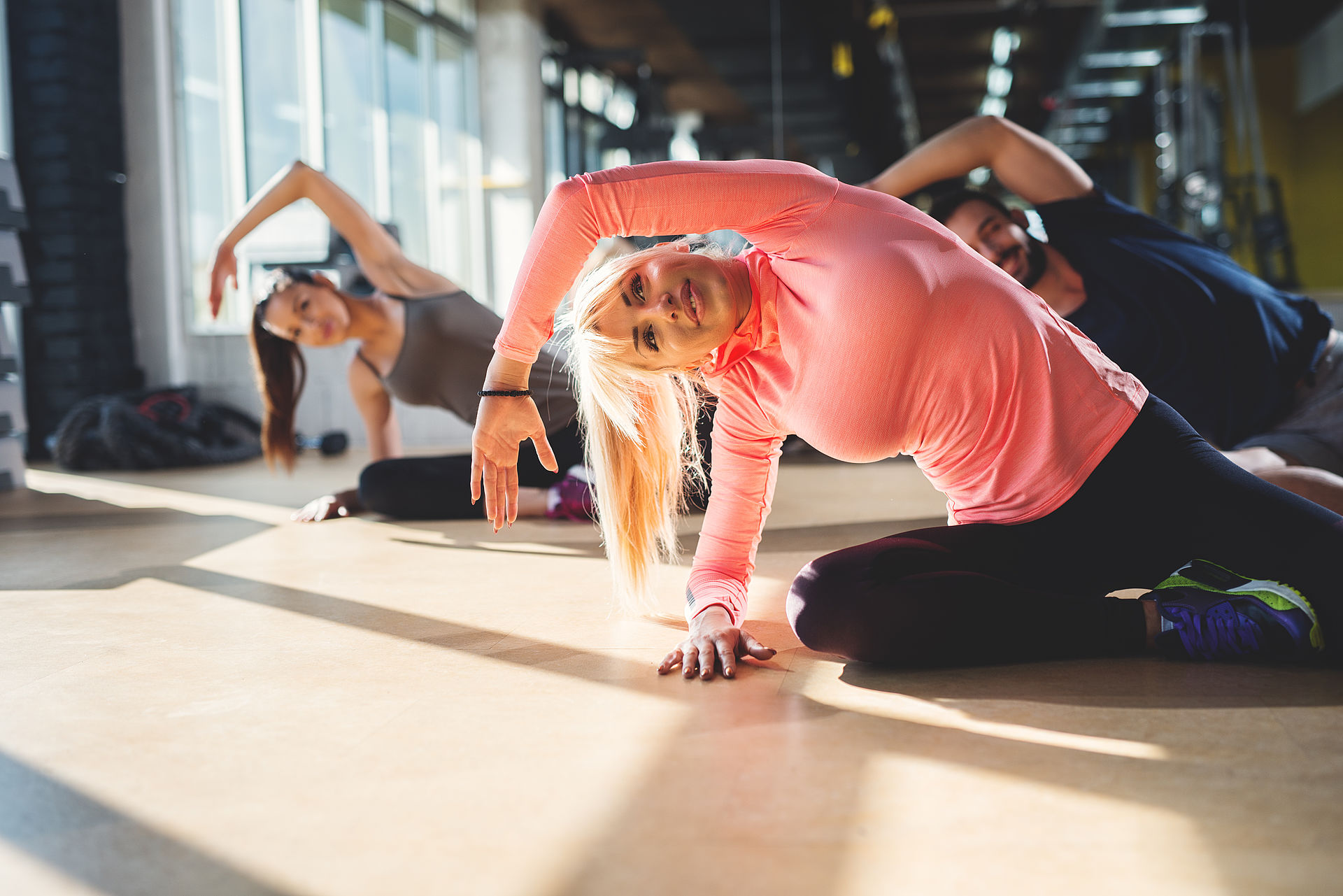 Group of athletes doing stretching exercises in fitness studio.