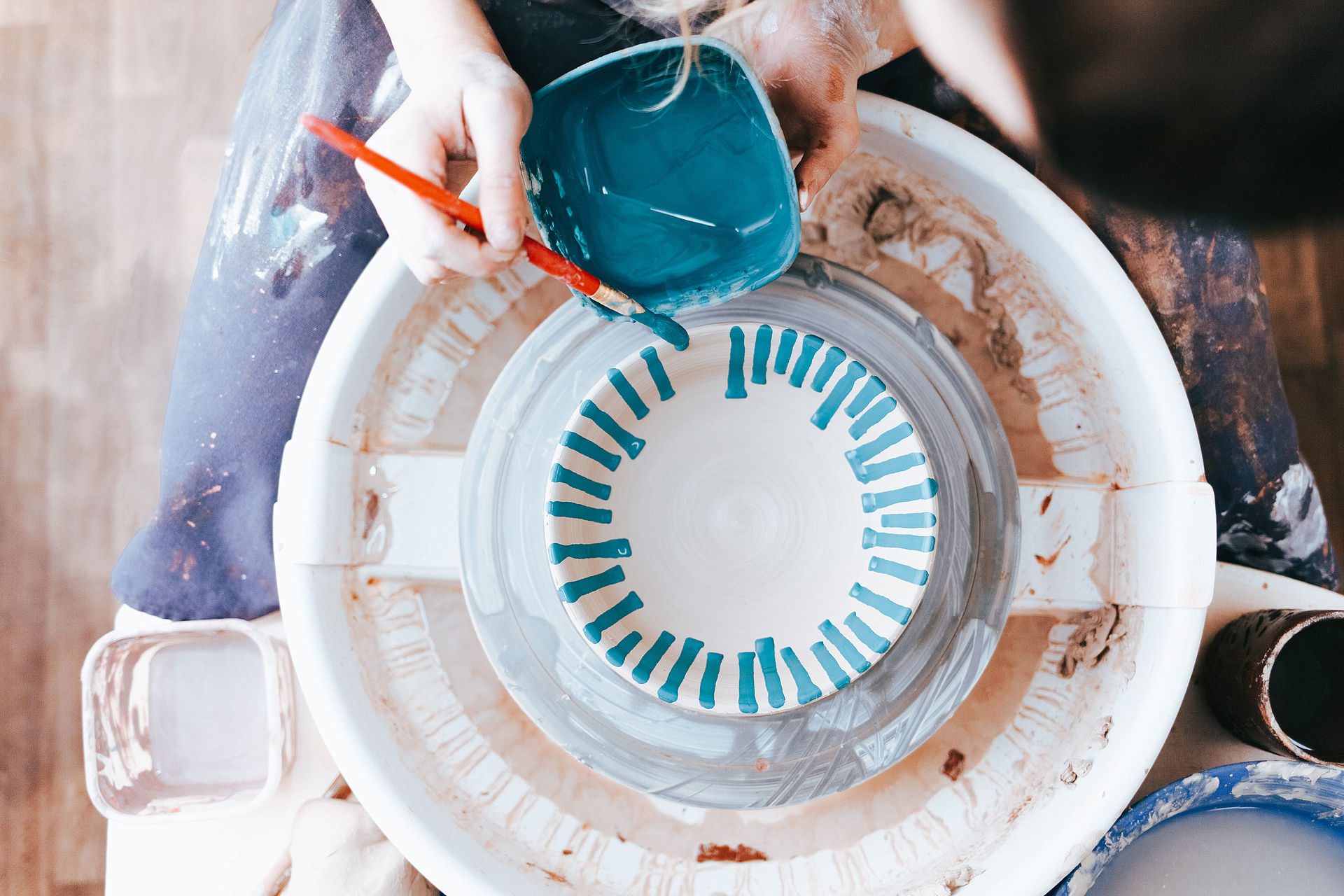Professional potter works on painting plates in the workshop. Wo